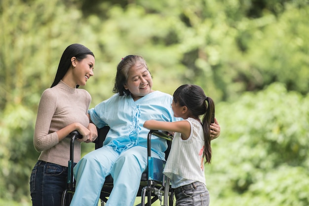 Nonna felice in sedia a rotelle con sua figlia e nipote in un parco, vita felice tempo felice.