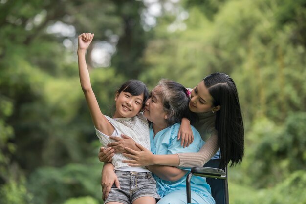 Nonna felice in sedia a rotelle con sua figlia e nipote in un parco, vita felice tempo felice.