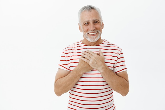 Nonno anziano toccato e lusingato con la barba che sembra felice e grato