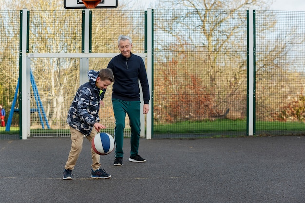 Nonno e bambino a tutto campo che giocano a basket