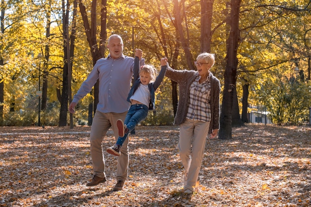 Nonno e nonna che giocano con il nipote in un parco