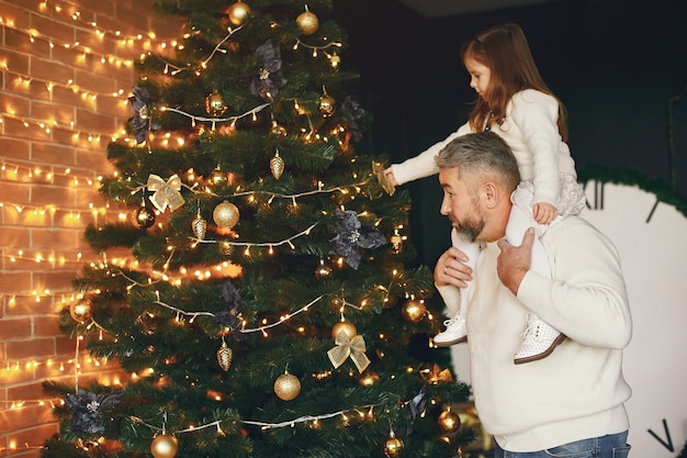 Nonno seduto con sua nipote. Celebrare il Natale in una casa accogliente. Uomo in un maglione lavorato a maglia bianco.