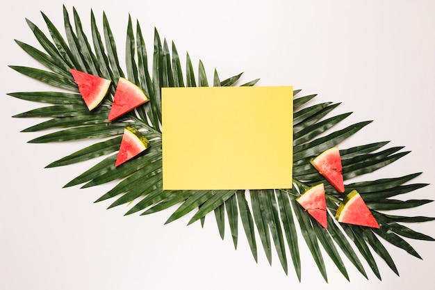 Nota appiccicosa gialla ed anguria rossa affettata su foglia di palma
