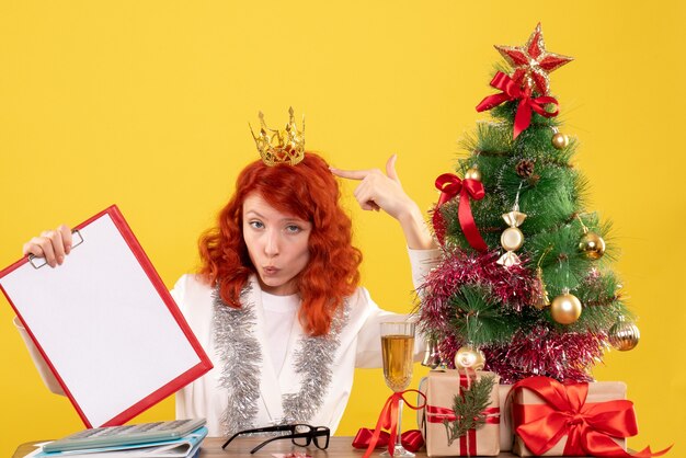 Nota di archivio femminile della tenuta del medico di vista frontale intorno all'albero di natale ed ai regali