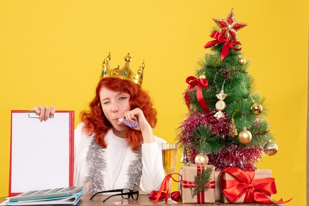 Nota di archivio femminile della tenuta del medico di vista frontale intorno all'albero di natale ed ai regali
