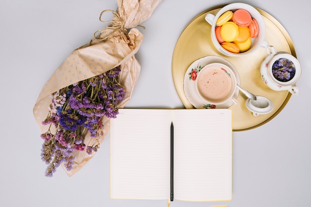 Notebook con bouquet di fiori e biscotti sul vassoio