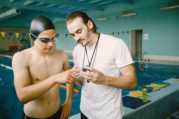 Nuotatore e allenatore che discutono in piscina. etnia europea. Centro ricreativo.