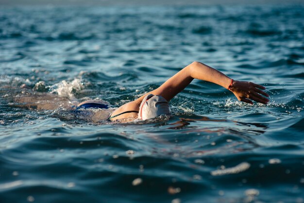 Nuotatore femminile con cappuccio e occhiali di protezione nuotare in acqua