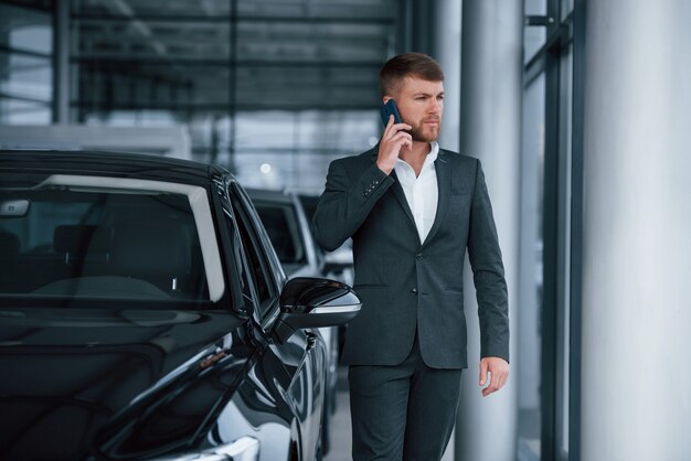 Nuovi affari in arrivo. Uomo d'affari barbuto elegante moderno nel salone dell'automobile