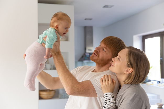 Nuovi genitori felici che tengono e che esaminano bambino gridante