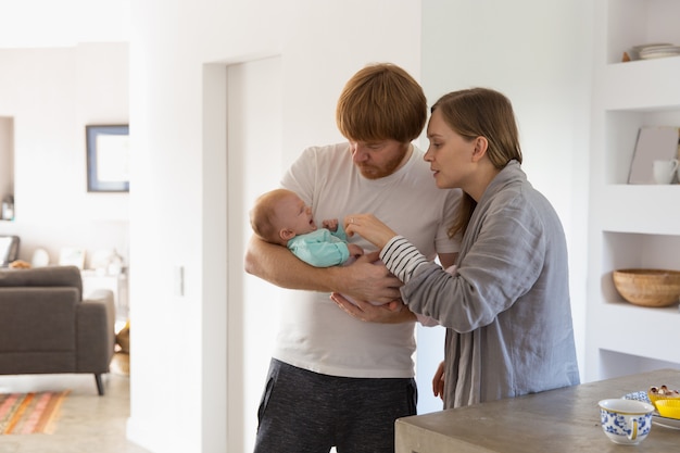 Nuovi genitori preoccupati che tengono e oscillano piangendo bambino