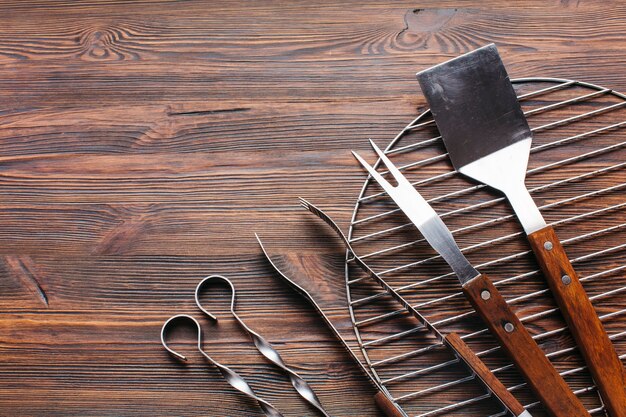 Nuovi utensili metallici del barbecue su fondo di legno