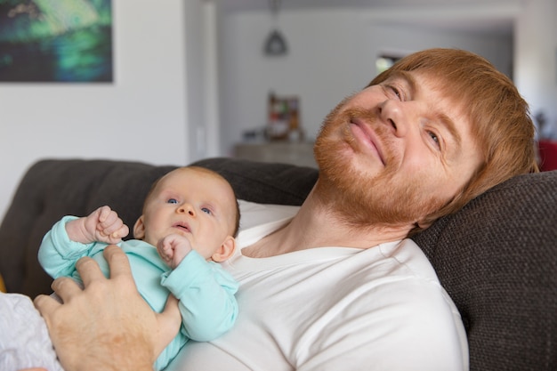 Nuovo padre positivo pacifico e suo figlio che si rilassano sull'allenatore