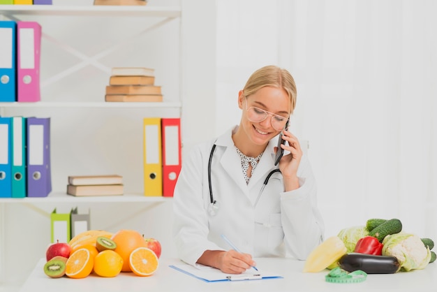 Nutrizionista di smiley del colpo medio che parla sul telefono