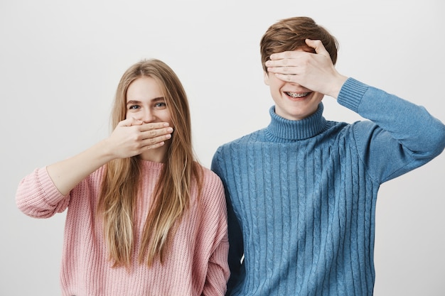 Occhi vicini sorridenti felici sorridenti della bocca e del tipo della copertura della ragazza con la mano