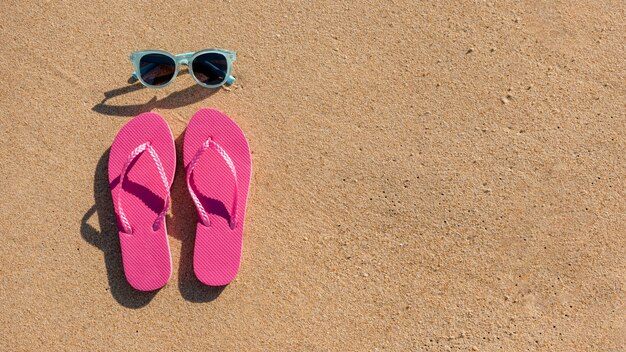 Occhiali da sole e ciabatte da spiaggia sulla sabbia