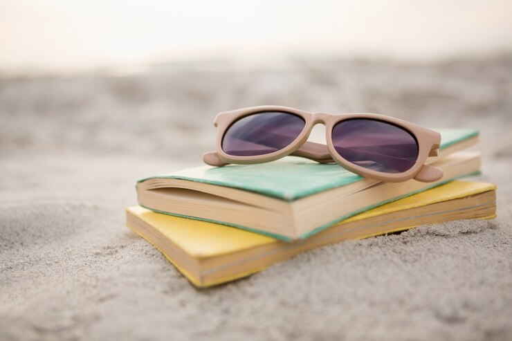 Occhiali da sole e libri sulla sabbia
