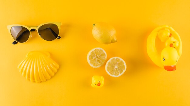Occhiali da sole; pettine; anatra di gomma e limone su sfondo giallo