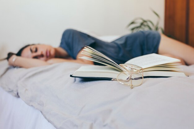 Occhiali e libro vicino a donna addormentata