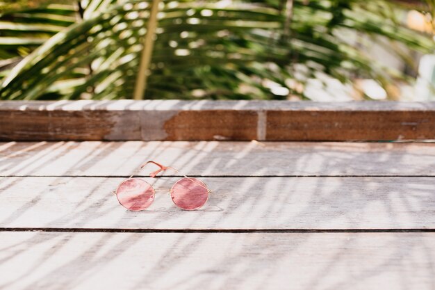 Occhiali femminili alla moda che si trovano sulla tavola di legno.