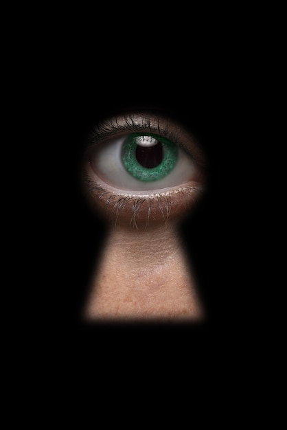 Occhio verde che guarda attraverso il buco della serratura