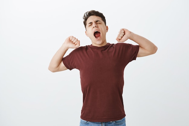 Odio svegliarti presto. Ragazzo bello sbadiglio assonnato in camicia rossa