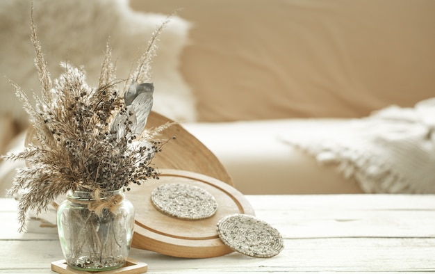 Oggetti decorativi nell'accogliente interno della stanza, un vaso con fiori secchi su un tavolo di legno chiaro.