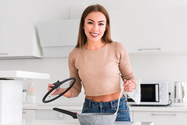 Oggetti della cucina della tenuta della donna nella vista frontale delle mani