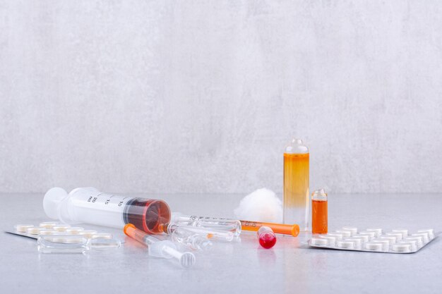 Oggetti medici, pillole e siringhe sulla superficie di marmo. Foto di alta qualità