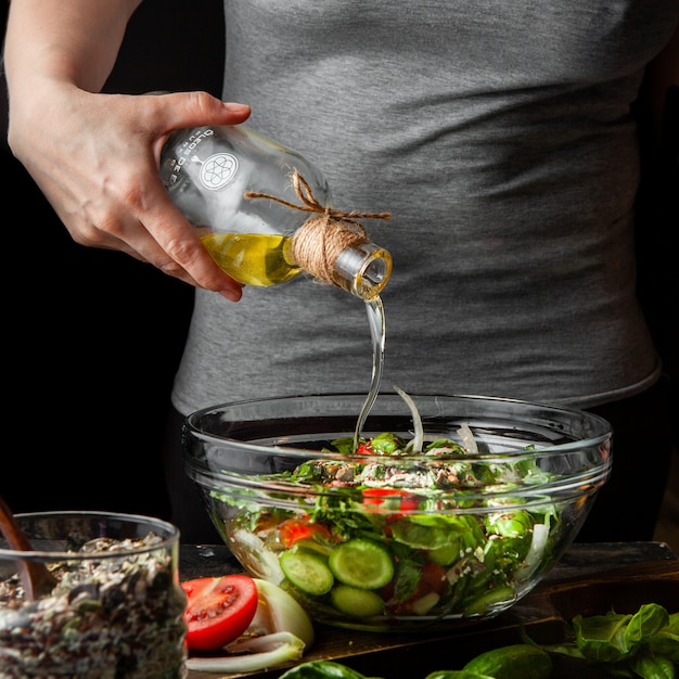 Olio d'aggiunta femminile nella vista laterale del pasto sano.