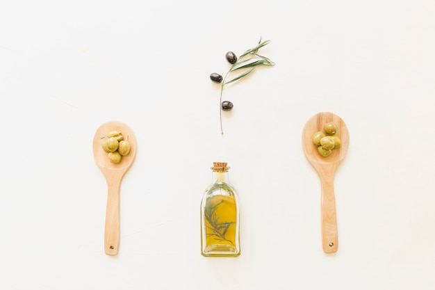 Olio d&#39;oliva in bottiglia e cucchiai con olive