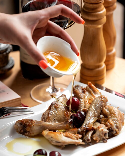 Olio di versamento della donna sulle coscie di pollo arrostite