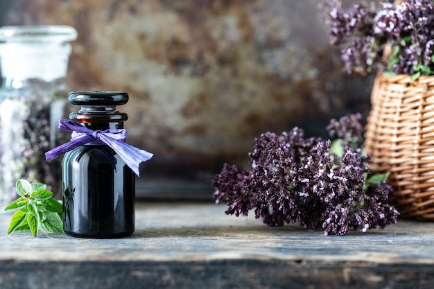 Olio essenziale di origano in bottiglia di vetro su fondo di legno. copia spazio