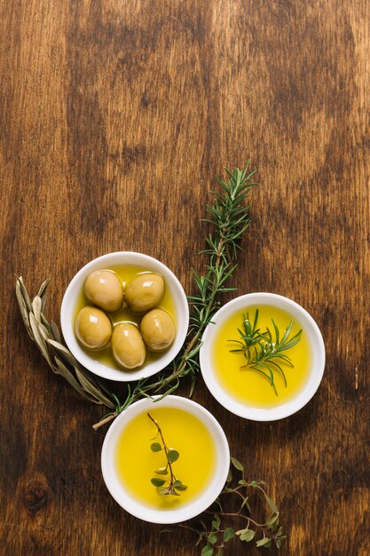 Olive con olio d'oliva e scodelle di rosmarino e copia-spazio