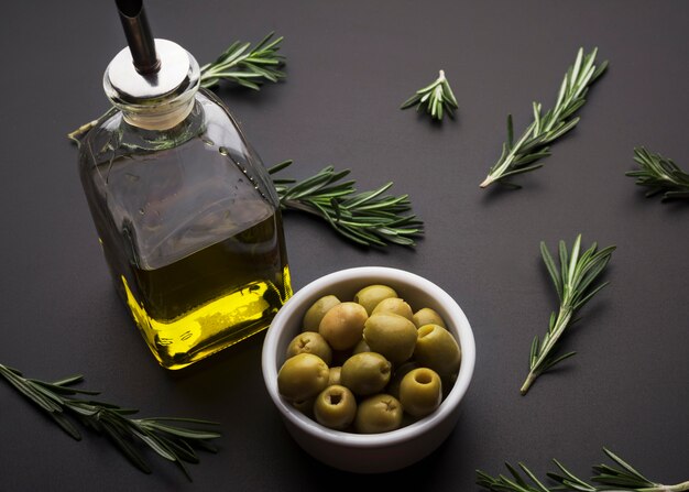 Olive e olio d&#39;oliva e rosmarino sulla superficie nera dell&#39;ardesia