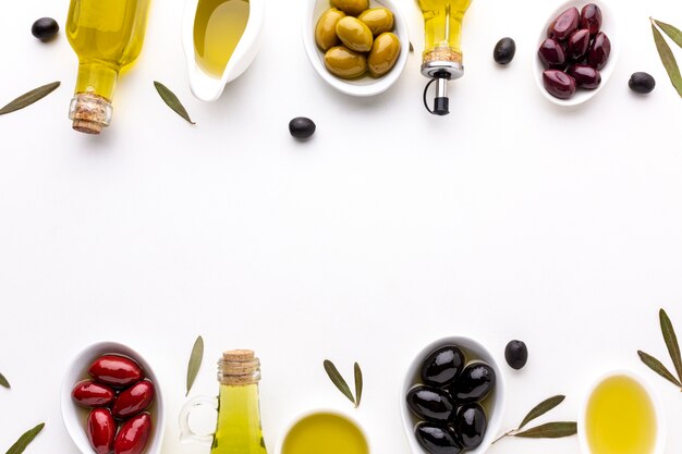 Olive nere gialle rosse di vista superiore in cucchiai con le bottiglie di olio e lo spazio della copia
