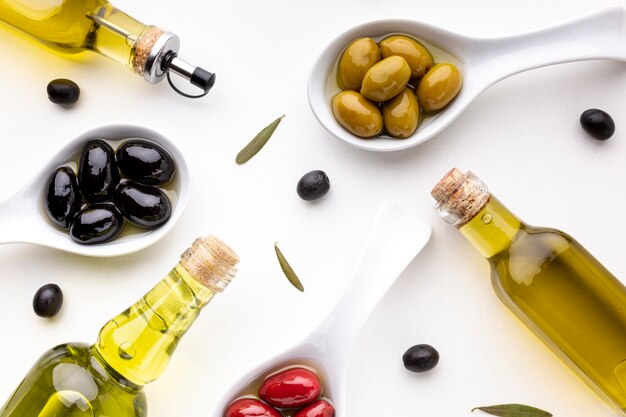 Olive nere rosse gialle piane in cucchiai con bottiglie di olio