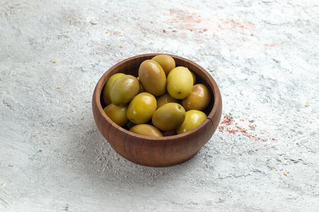 Olive verdi di vista frontale all'interno del piccolo piatto su uno spazio bianco