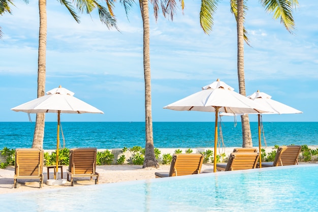 Ombrellone e sdraio intorno alla piscina all'aperto nel resort dell'hotel con spiaggia sull'oceano e palme da cocco