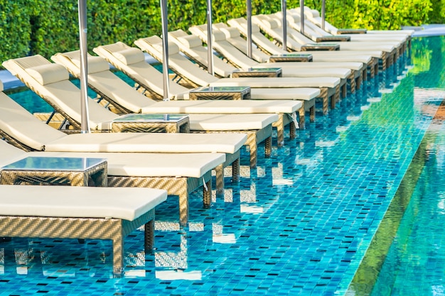 Ombrellone e sedia divano intorno alla piscina all'aperto in hotel resort per vacanze