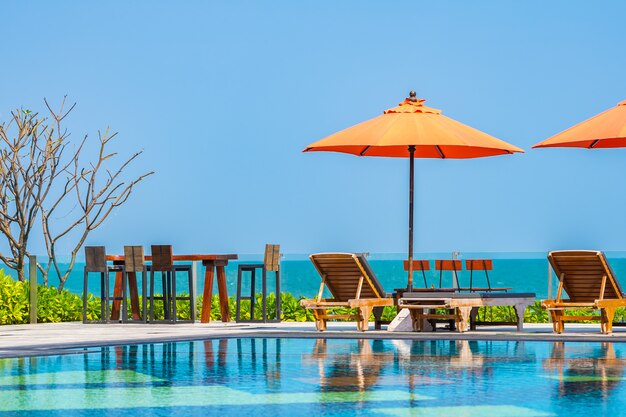 Ombrellone e sedia intorno alla piscina all'aperto vicino al mare nel resort dell'hotel