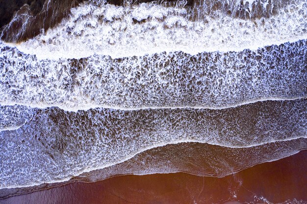 Onde con acqua schiumata in spiaggia