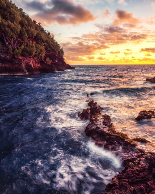 Onde di oceano che si schiantano sulle rocce durante il tramonto