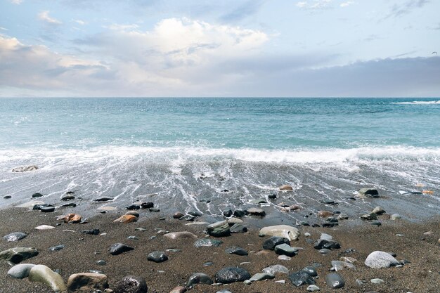 Onde schiumose del mare che lavano la riva sabbiosa