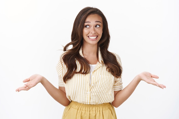 Oops, ragazza che evita il contatto visivo per non farsi sorprendere a mentire. Sciocca giovane ragazza che alza le spalle con le mani aperte lateralmente, sorridendo distogliendo lo sguardo colpevole, cercando di convincere che non ha idea di cosa sia successo