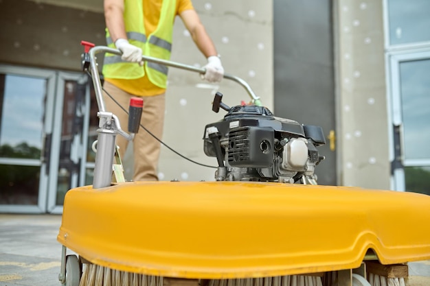 Operaio che applica una spazzatrice stradale sul cantiere