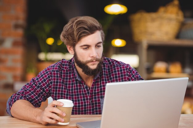 operaio concentrato usando il suo computer portatile in un coffee shop