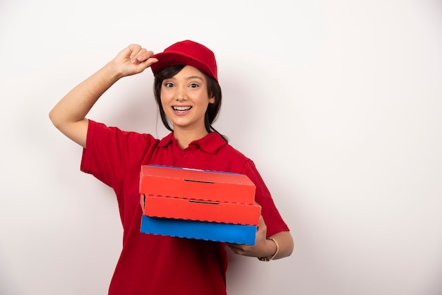 Operaio di consegna pizza femminile in piedi con tre cartoni di pizza.