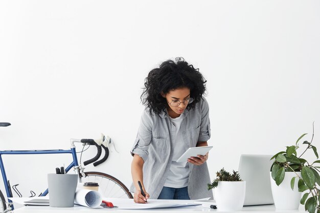 Operaio di design piuttosto femminile con capelli scuri voluminosi che indossa una camicia casual