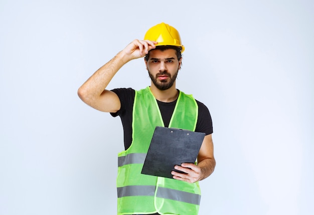 Operaio edile in uniforme in possesso di un piano di progetto.